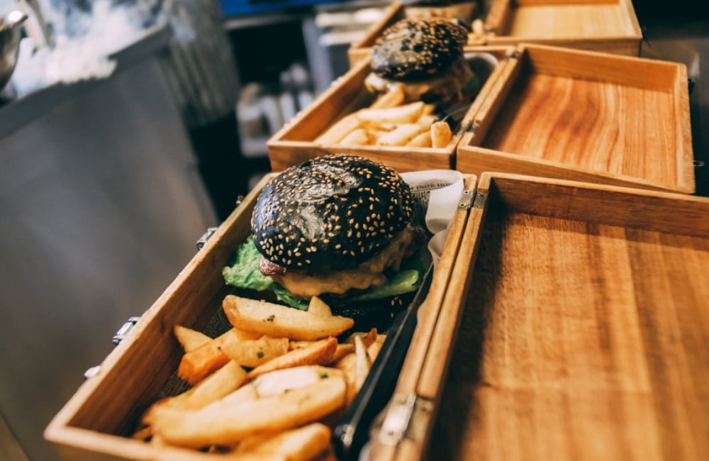 black bun burger and chips served in a wooden box