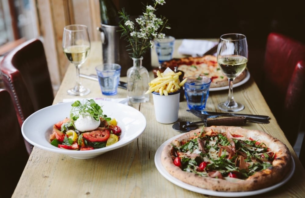 restaurant table with pizza, fries, and salad