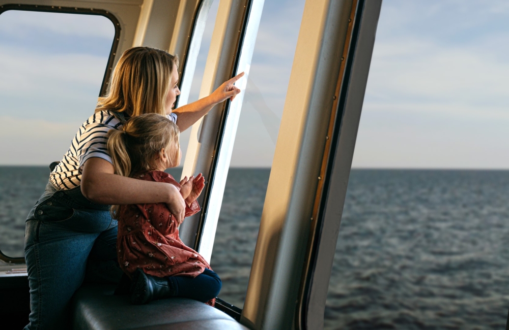 mother and young daughter looking out to sea from the ferry