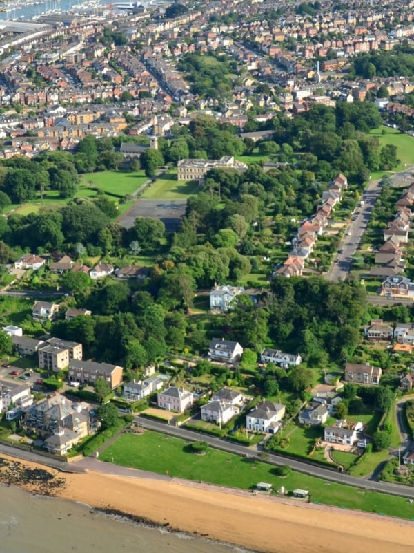 an aerial view of cowes seafront, showing green parks and the beach