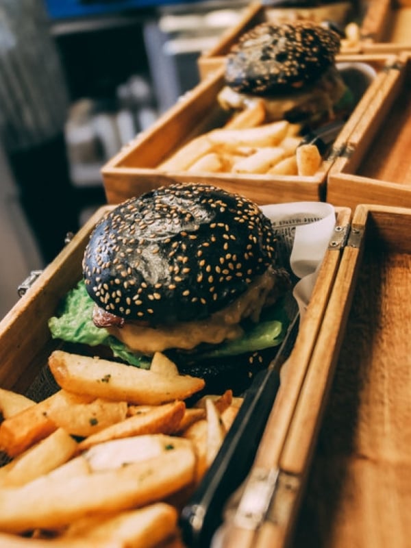 black bun burger and chips served in a wooden box