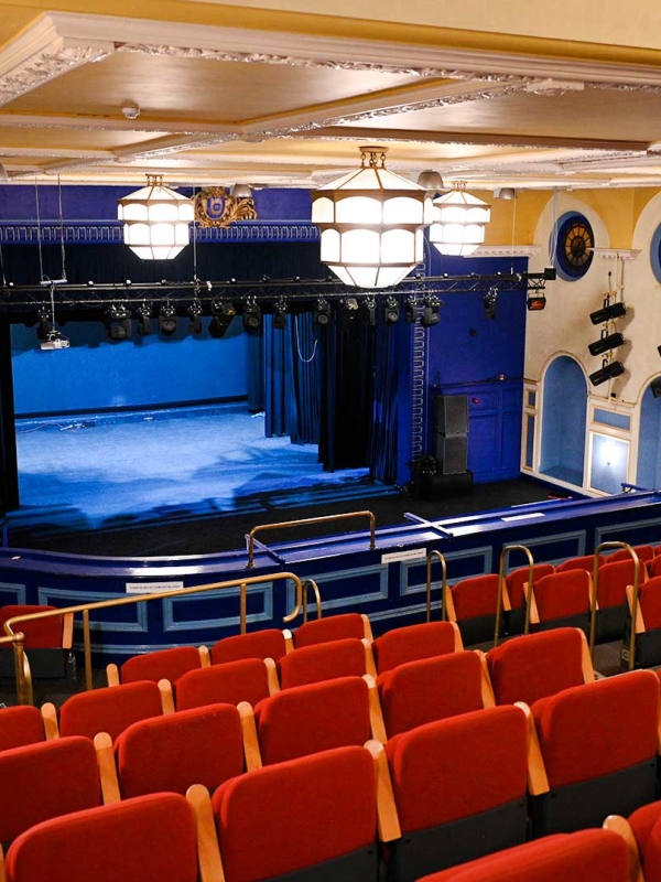 rows of red seats inside theatre auditorium with stage in the background