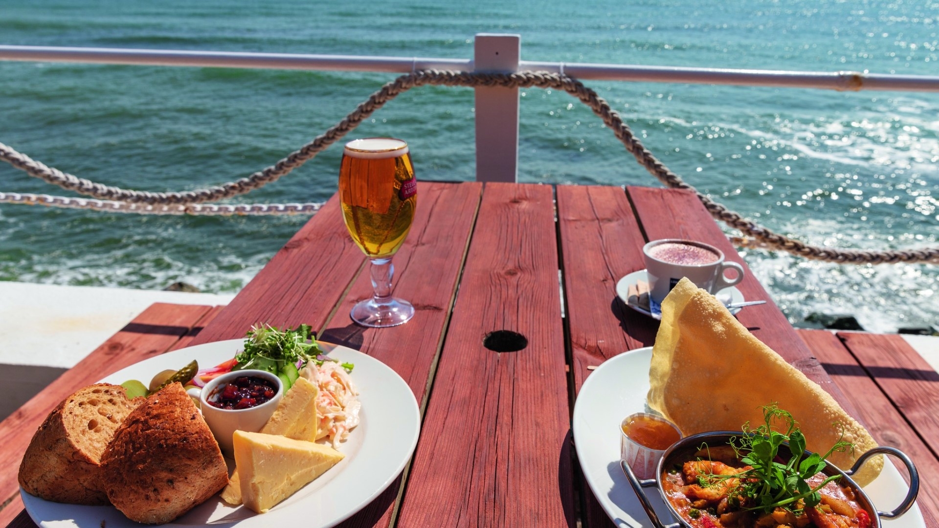meals on a picnic bench with the sea in the background