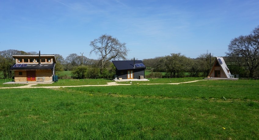 Three unique tiny homes nestled in a meadow with blue skies 