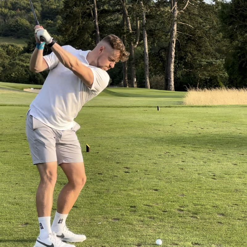 Josh Oddy swinging golf club on golf course