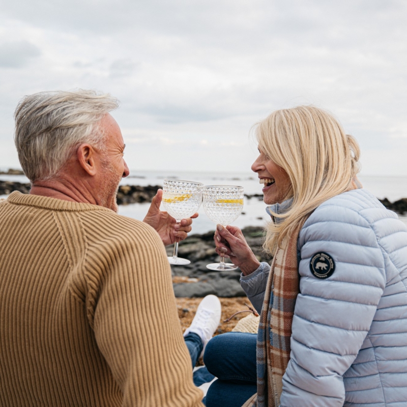 a smiling couple clink glasses of gin