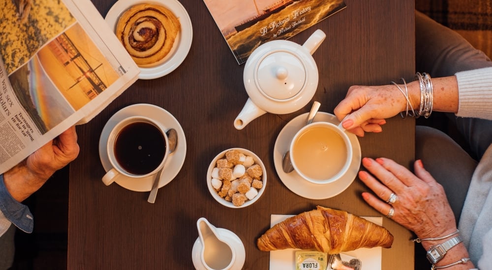 Aerial view of table with teapot, teacups and pastries 