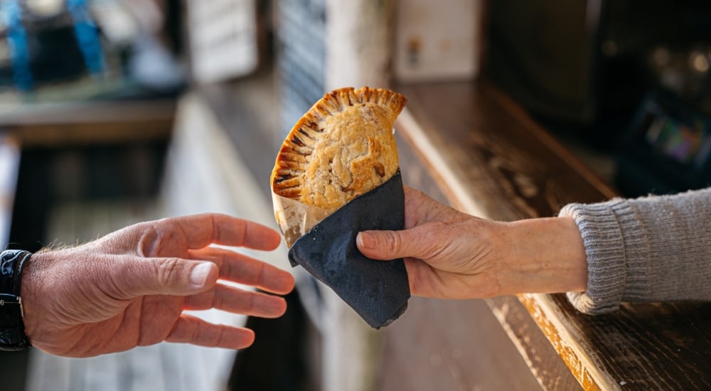 a crescent-shaped crab pasty with golden pastry wrapped in a napkin