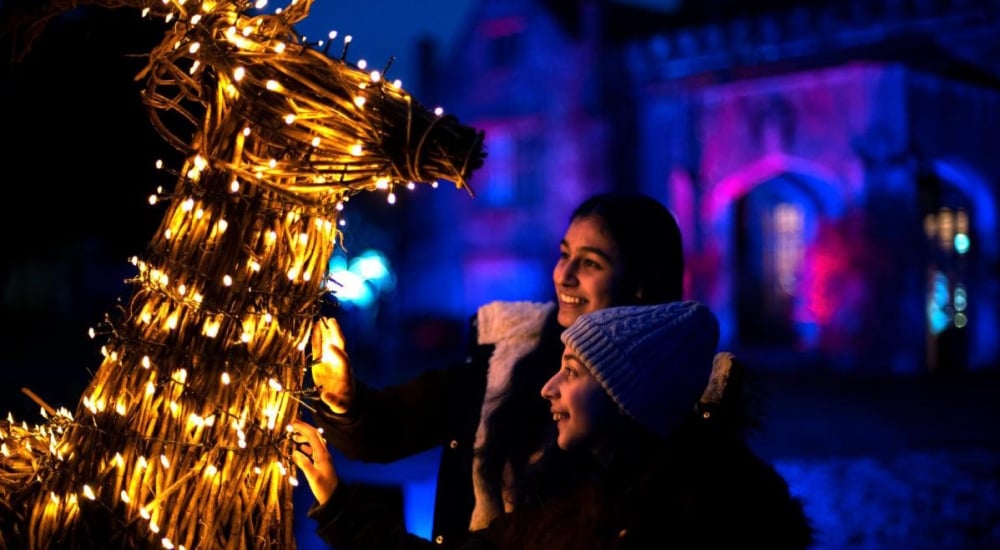 family looking at a reindeer model with fairy lights