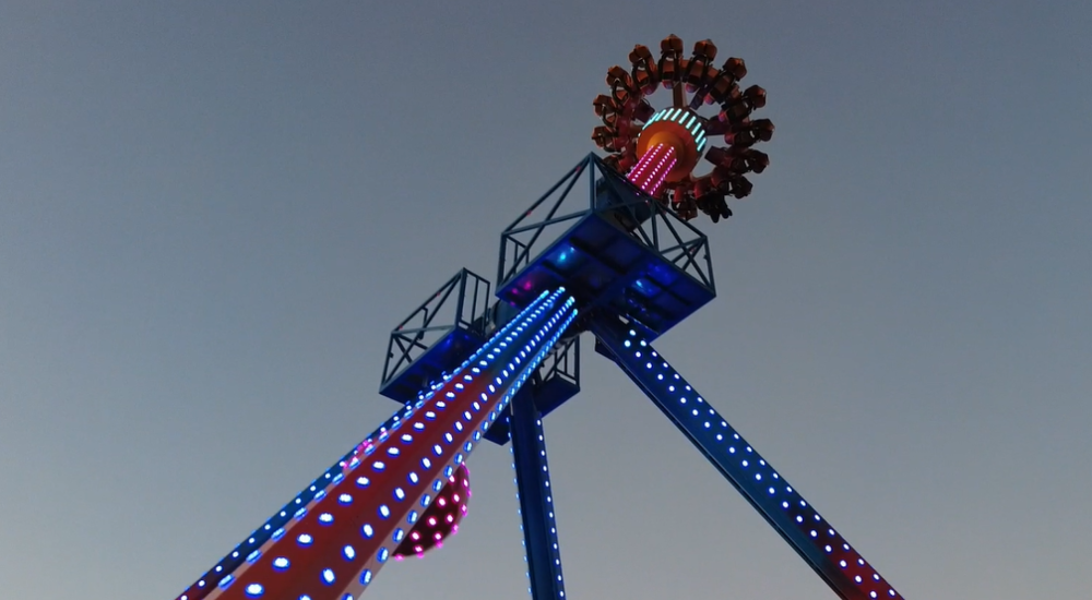 extinction, a large pendulum swing ride, lit up at night