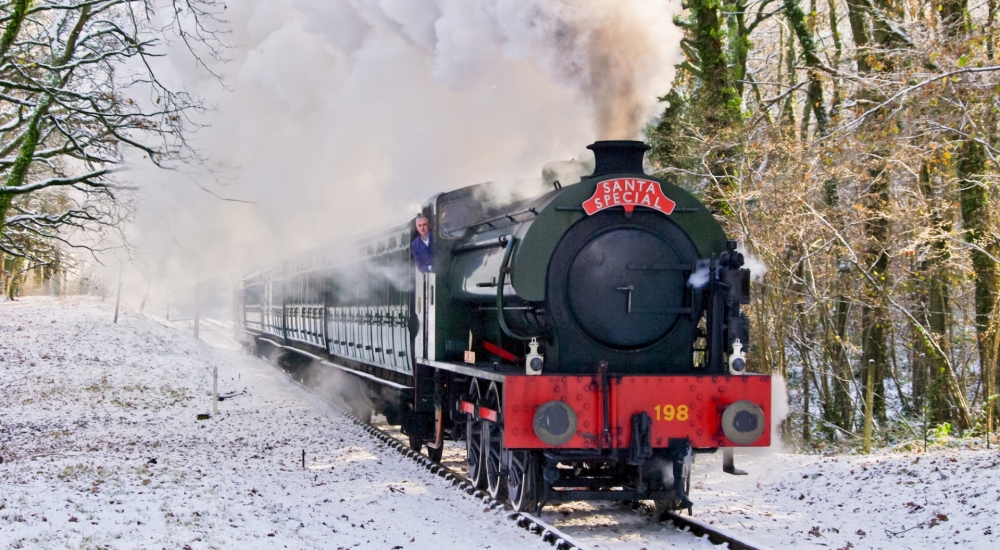 santa specials train travelling through the woods during snow