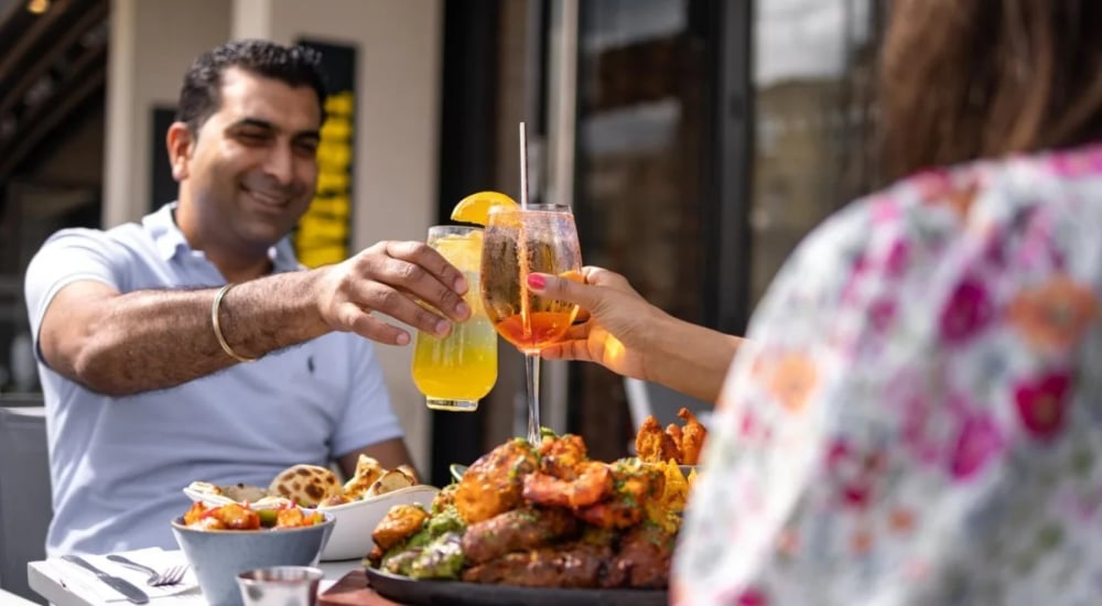 a couple enjoying colourful cocktails and indian food at tap n tandoor southampton