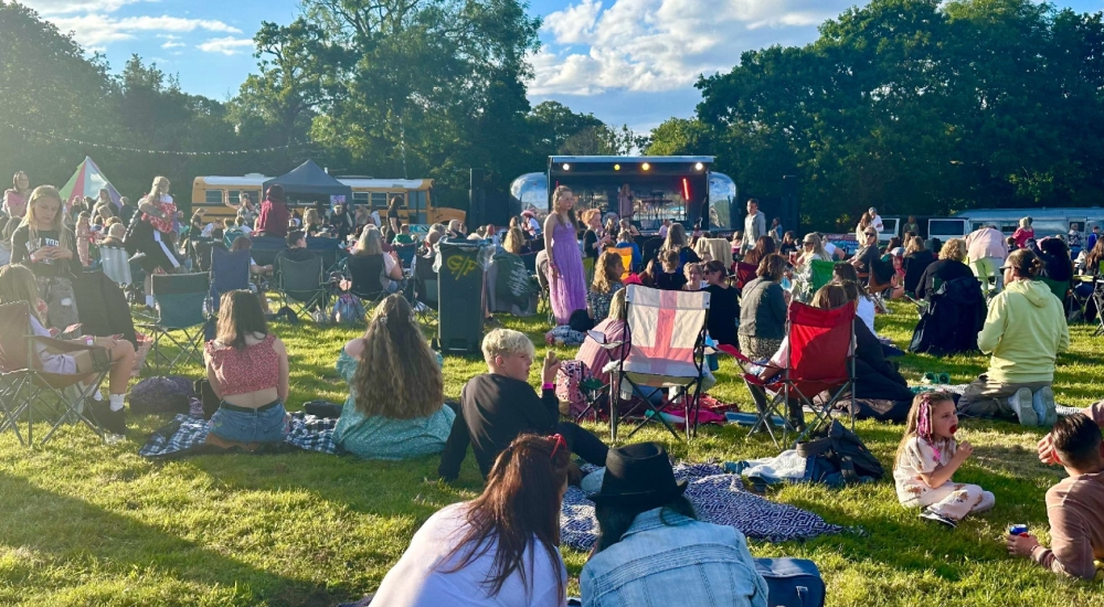 partygoers sat on the grass in front of the stage